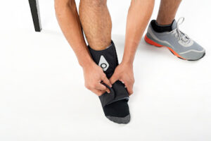 Hands adjusting a Squid Go cold compression wrap on an ankle