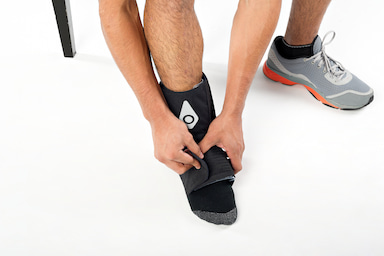 Hands adjusting a Squid Go cold compression wrap on an ankle