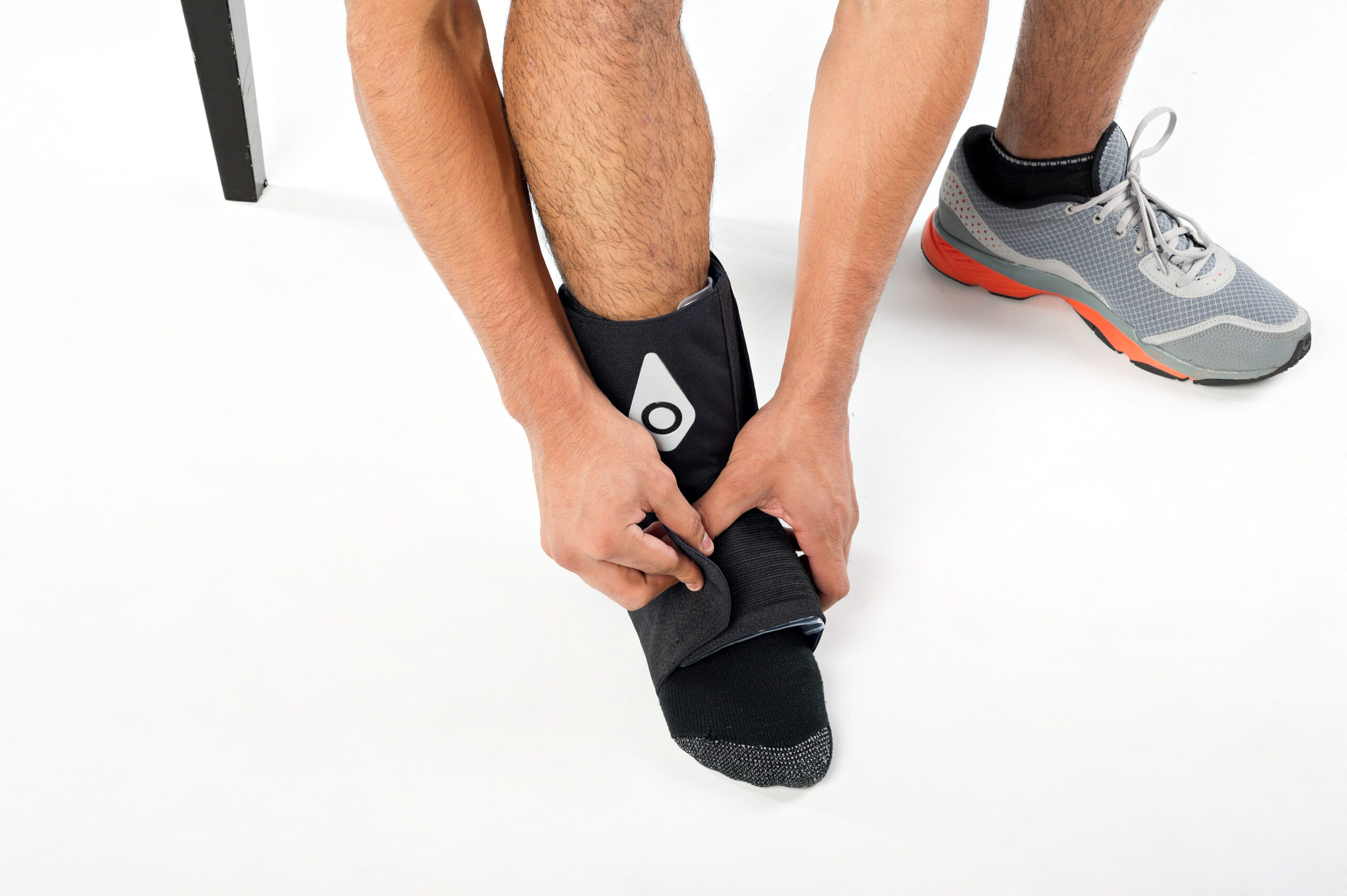 Hands adjusting a Squid Go cold compression wrap on an ankle