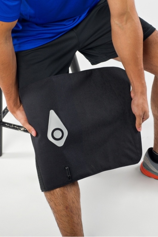 A person applying a Squid Go cold compression wrap to the leg
