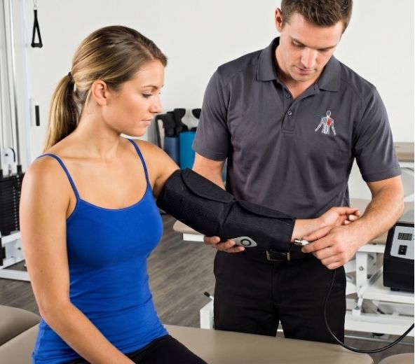 A trainer fitting a Squid Go cold compression wrap on a patient's arm